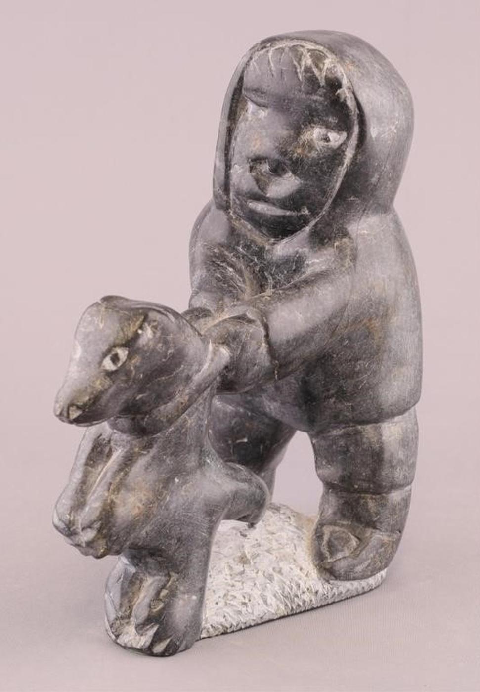 Johnny Inukpuk (1911-2007) - Grey stone carving of a Man Holding Back His Sled Dog