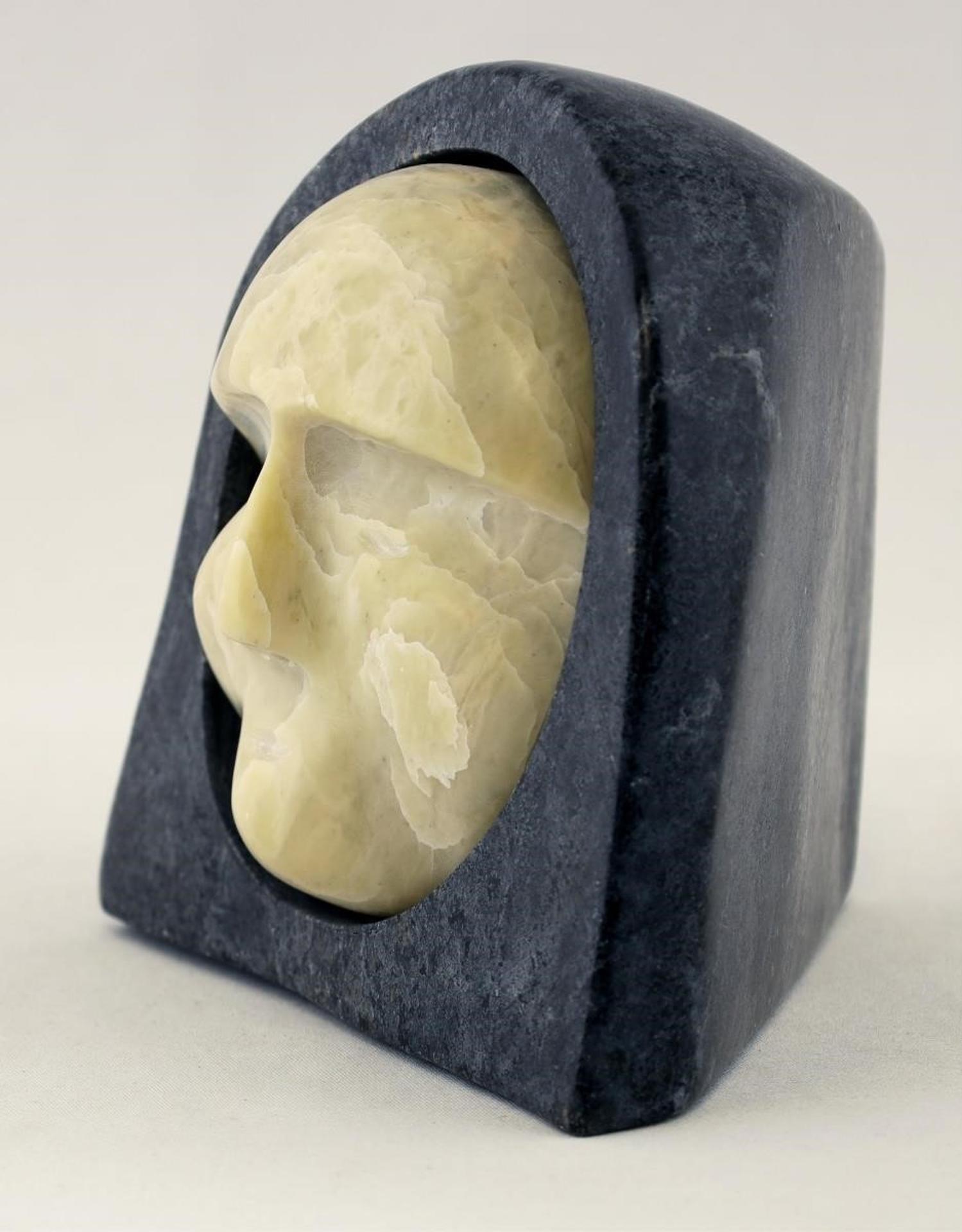 John Nevilue - a mixed stone carving of a face wrapped in an amauti parka hood