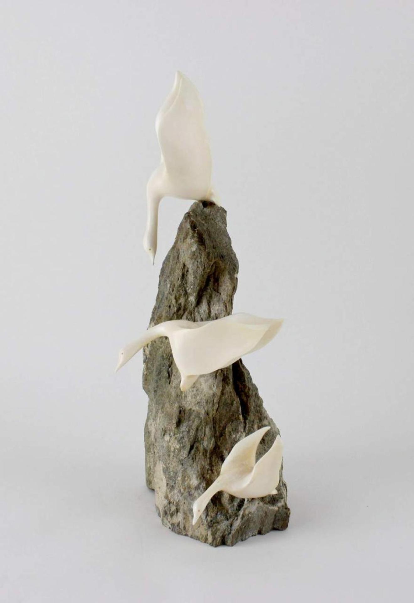 David Wong (1937-1998) - a large carved ivory and stone sculpture depicting three geese in flight atop a rock outcrop.