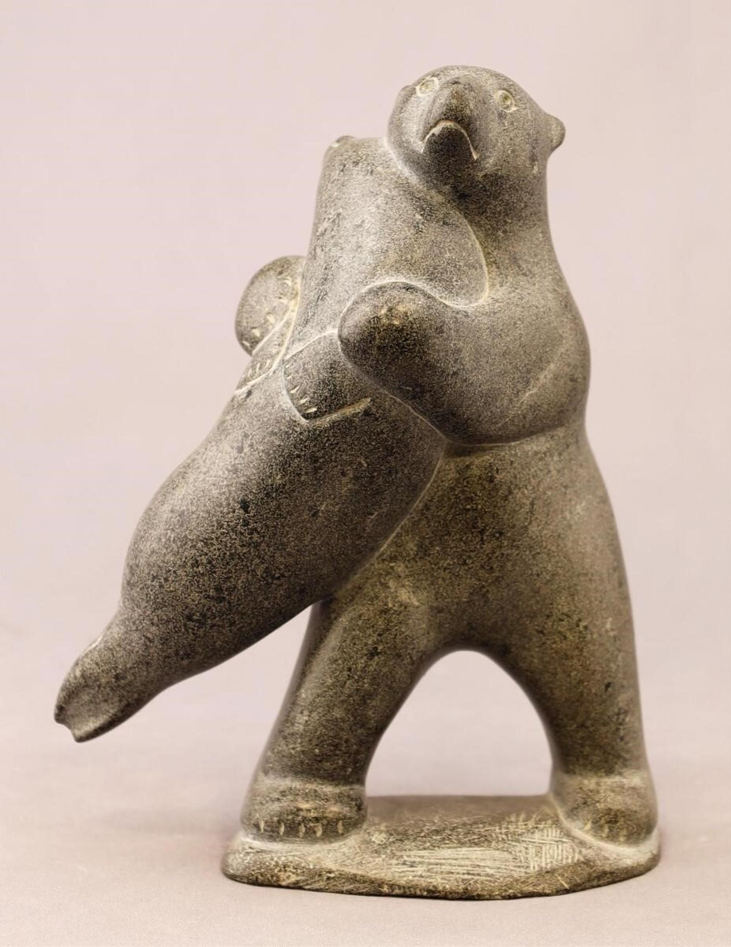 Paul Kavik (1948) - a grey stone carving of a Bear Carrying a Seal
