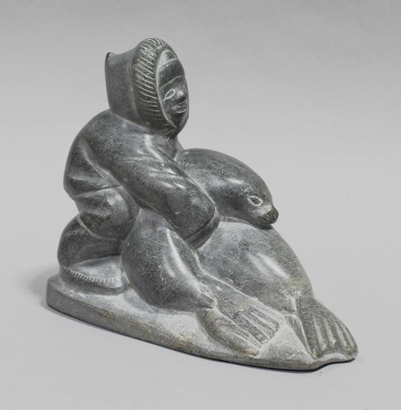 Tivi Ilisituk (1933-2012) - Light grey stone carving of a Seal Hunter with Two Seals