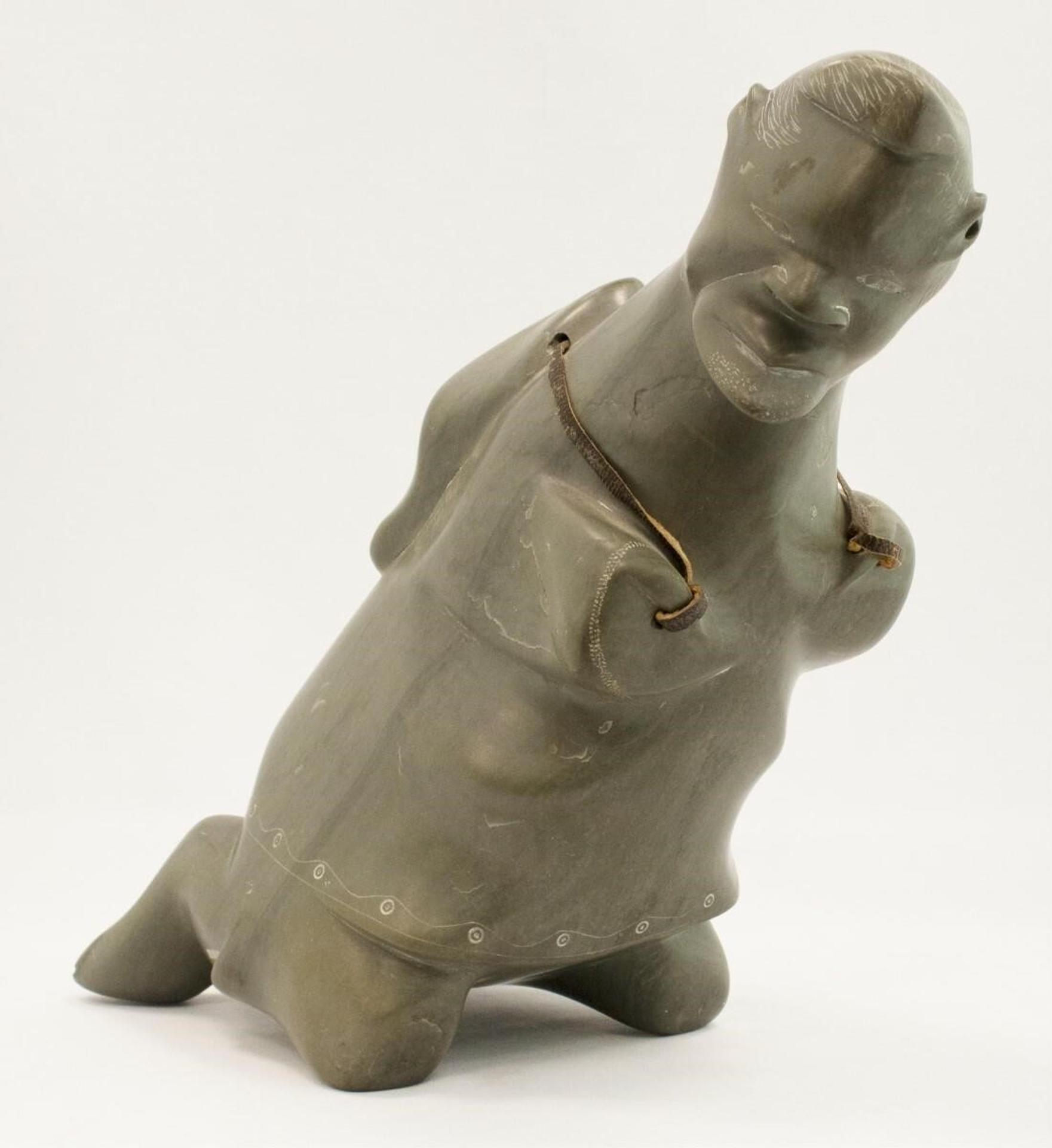 Davidee Eyaituq Eyitook (1935) - a green-grey stone carving of a Kneeling Man with a Sack on his back (hide strap)