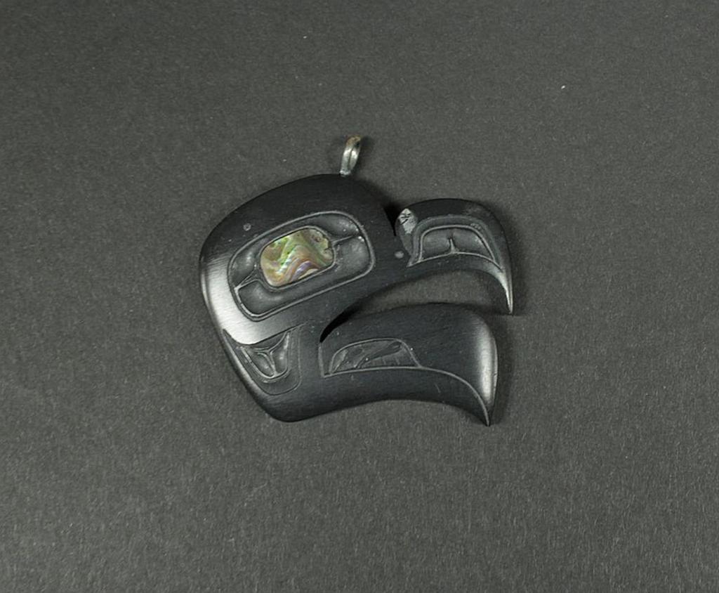 Harold Yeltatzie - a carved argillite pendant in the form of Eagle with inset abalone eyes