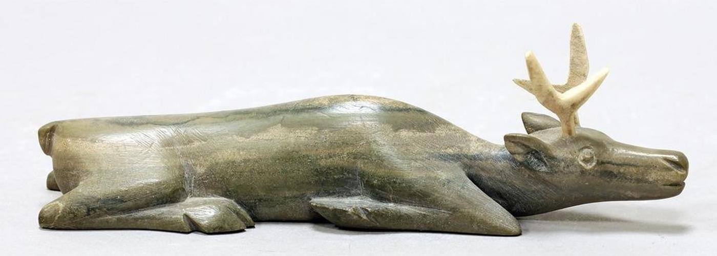 Annie Komek Kigiuna (1947) - A grey stone carving of a Resting Caribou