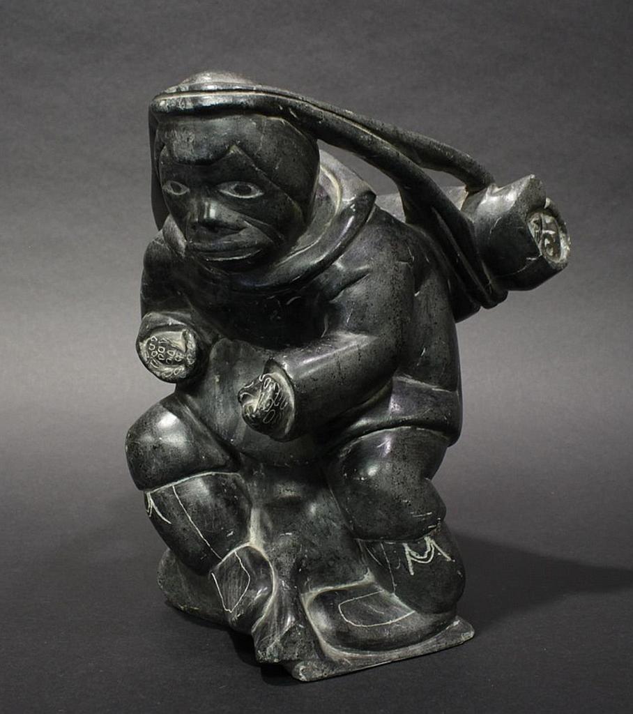 Levi Koma - a grey soapstone carving of an Inuk carrying a package on his back