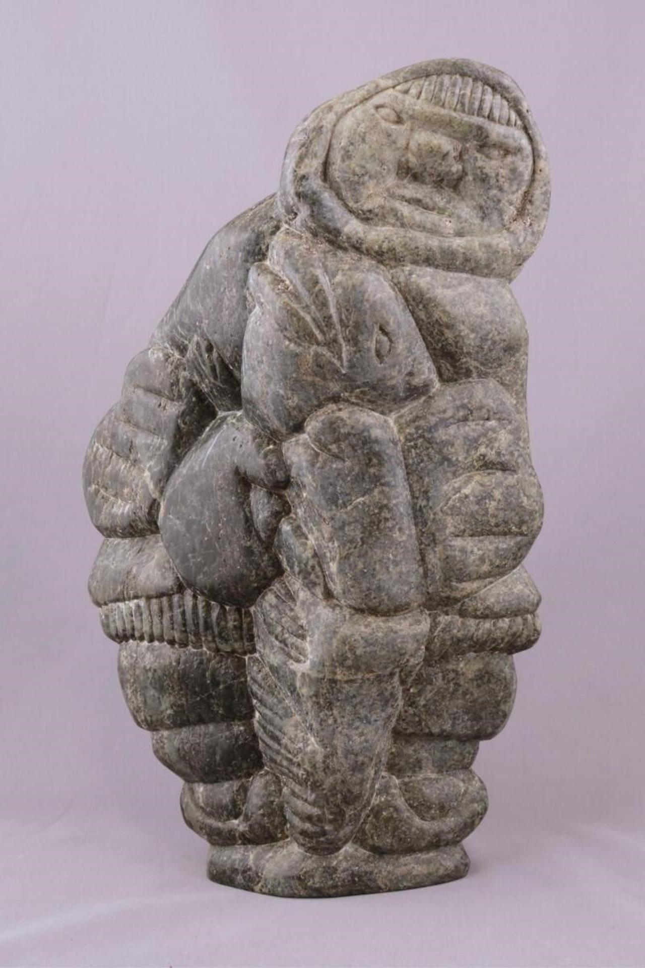 Charlie Inukpuk (1941) - a green stone carving of a Hunter with Catch