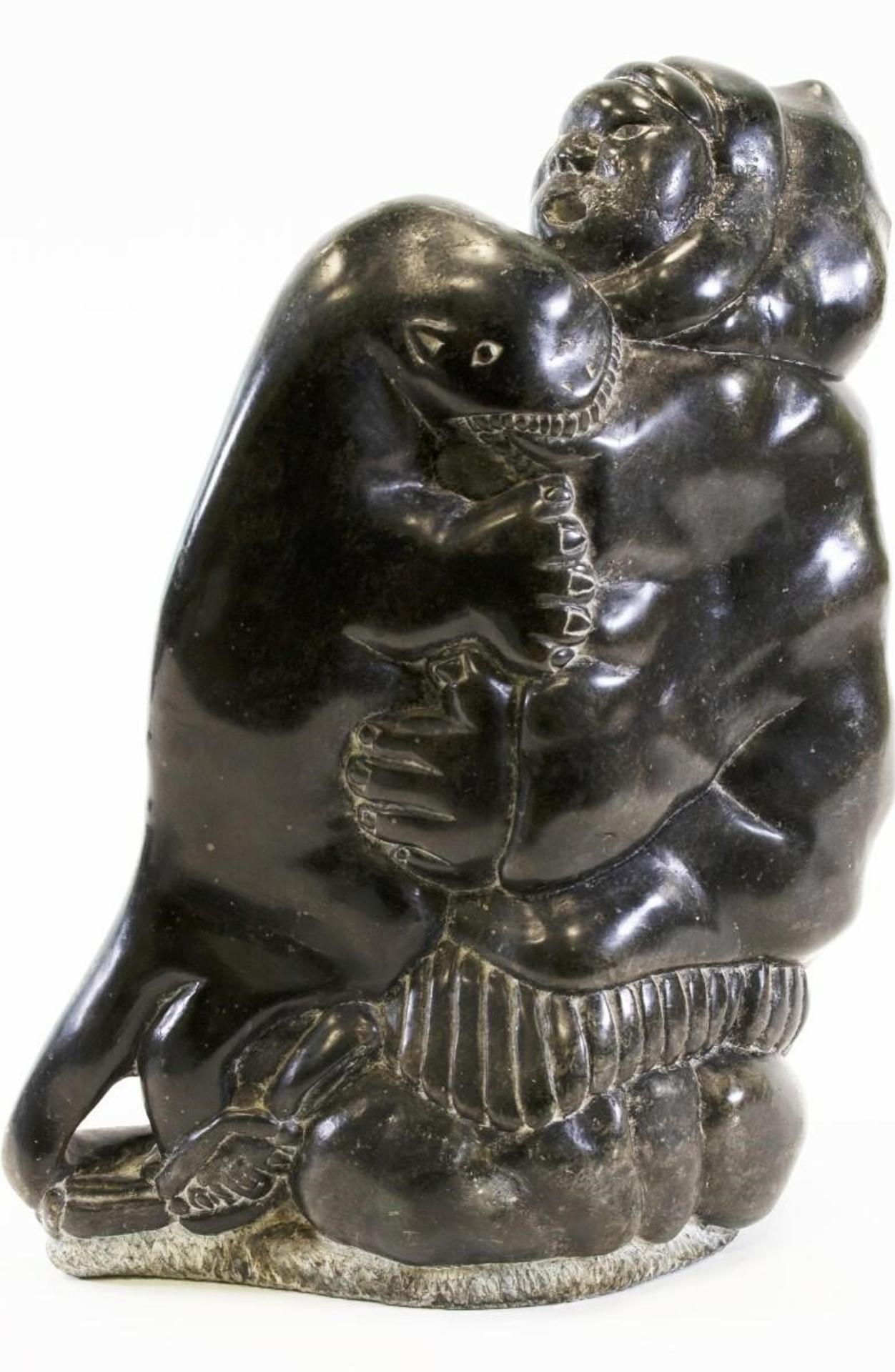 Charlie Inukpuk (1941) - a black-dark grey stone carving of a Hunter Wrestling an Otter